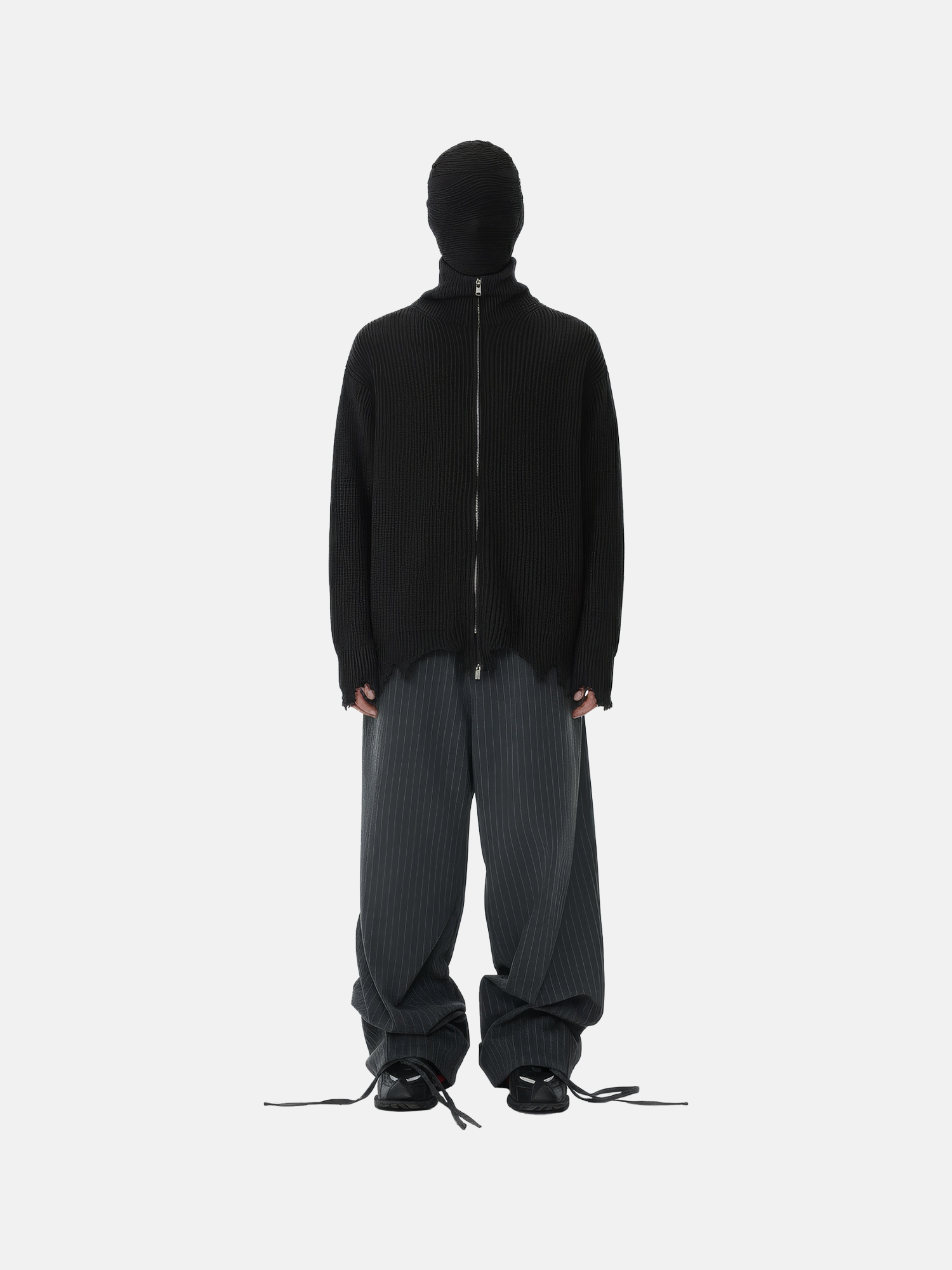Person wearing a black hoodie and gray pants on a white background
